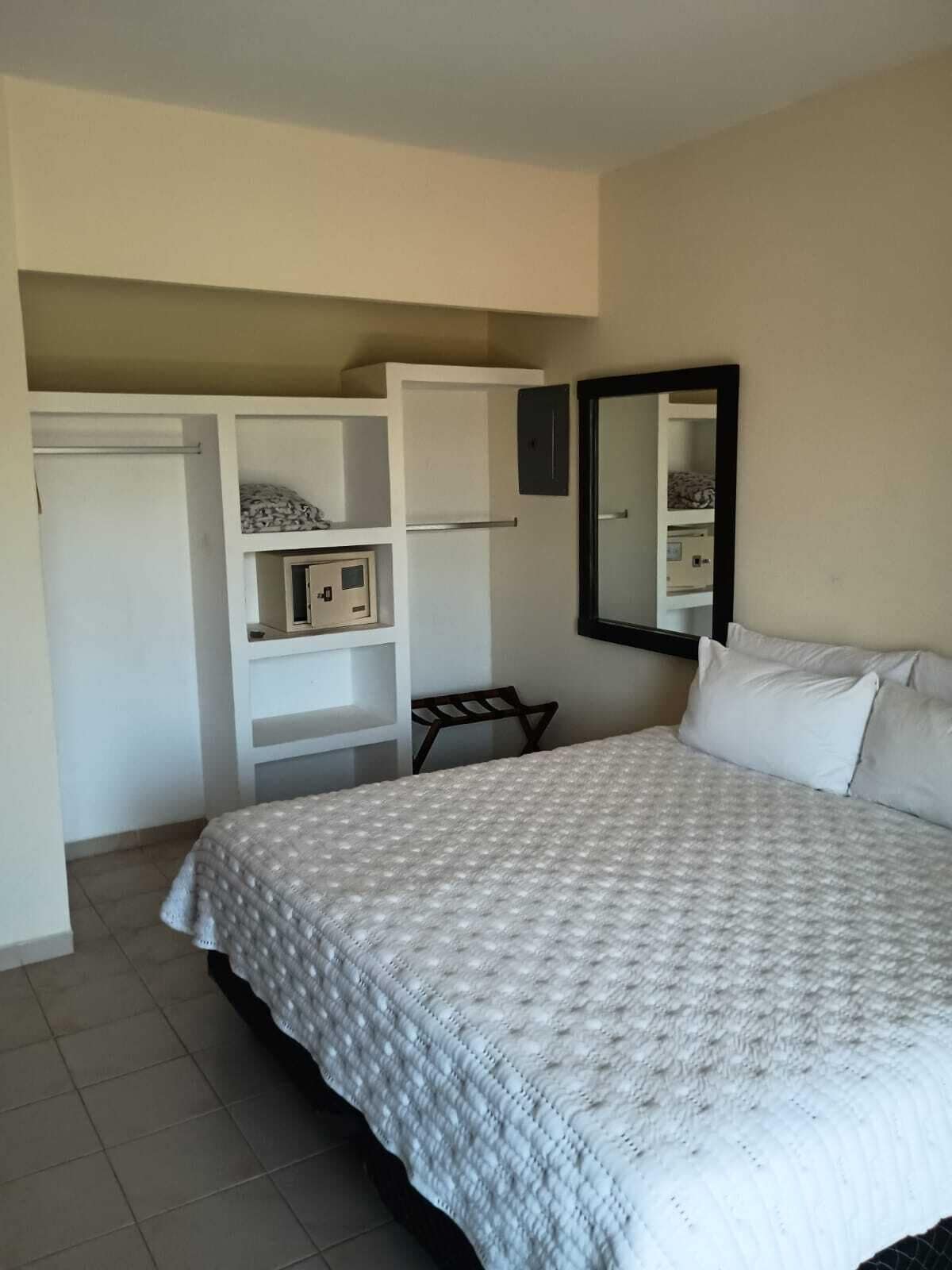 Une chambre à coucher avec un lit, une armoire, un miroir et un petit banc.