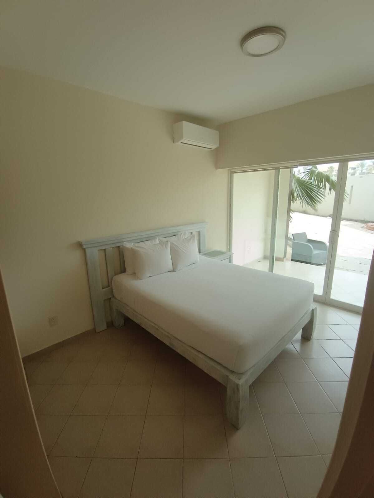 Una camera da letto con un letto, una ventola a soffitto e una porta scorrevole in vetro che dà su un'area esterna.