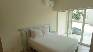 Una camera da letto con un letto, una ventola a soffitto e una porta scorrevole in vetro che dà su un'area esterna.