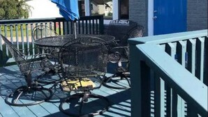 A deck with outdoor furniture and a blue door. - GOTL Coastal Cottage- Sunset Vacation Rentals (Geneva)