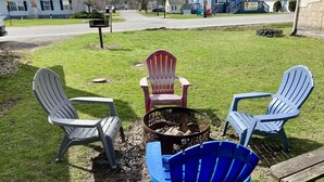 Ein Feuerkorb mit Adirondack-Stühlen auf einer Wiese.