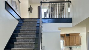 A multi-level home interior with a carpeted staircase, a kitchen area, and a dining space. - GOTL Winery Mansion- Sunset Vacation Rentals (Geneva)