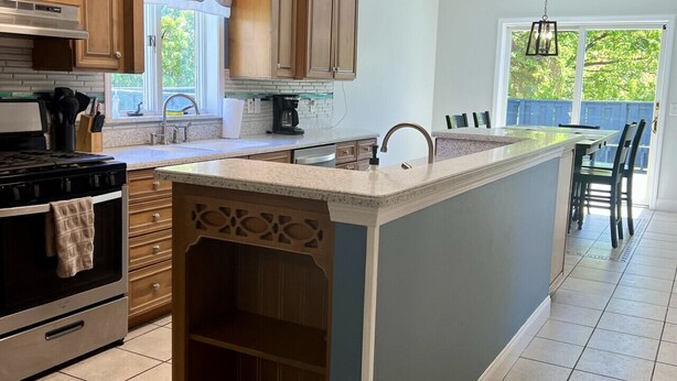 A kitchen with wooden cabinets, a built-in oven, a large island, and a view of the outdoors through a window. - GOTL Winery Mansion- Sunset Vacation Rentals (Geneva)