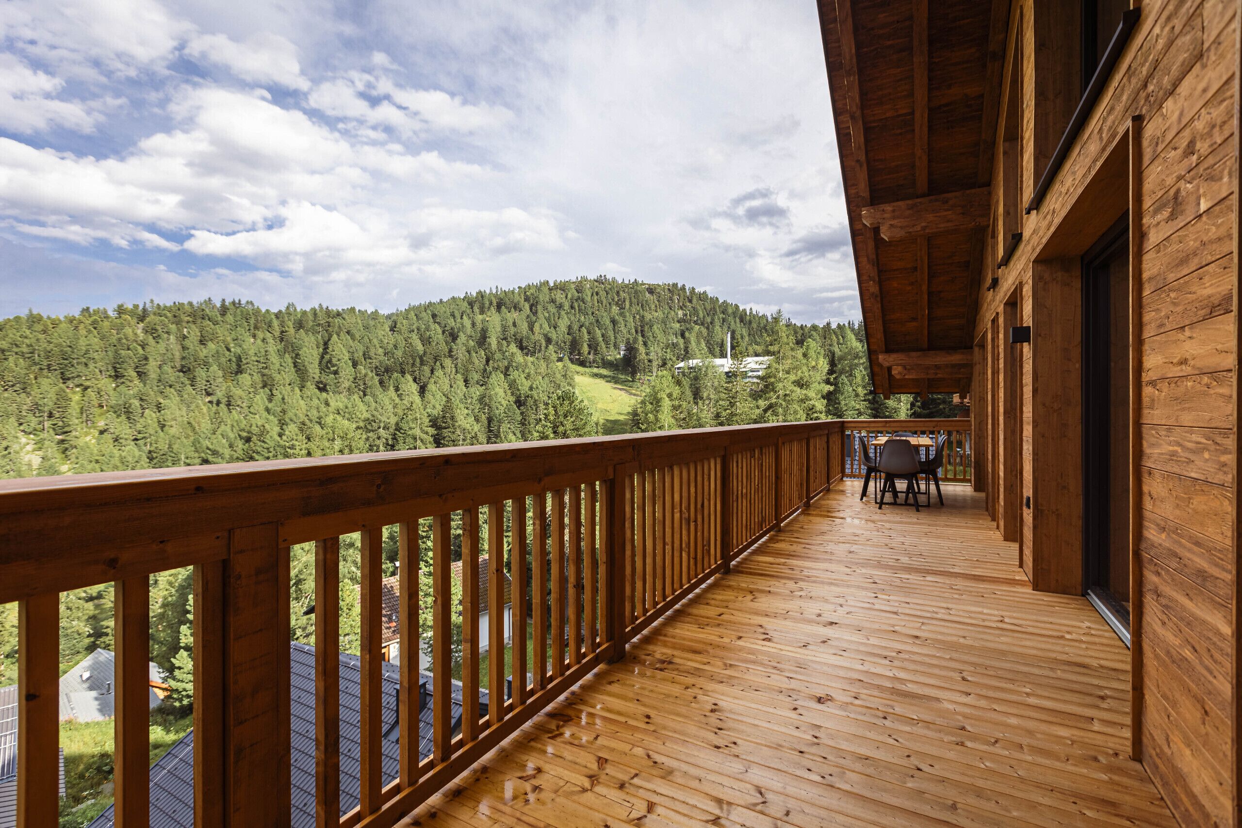 Eine Holzterrasse mit Blick auf einen bewaldeten Hügel und einen weißen Turm.