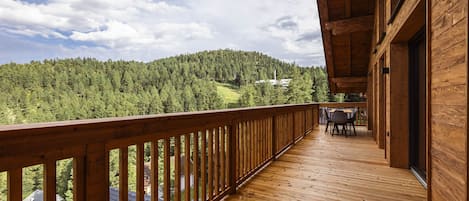 A wooden deck with a view of a forested hill and a white tower.