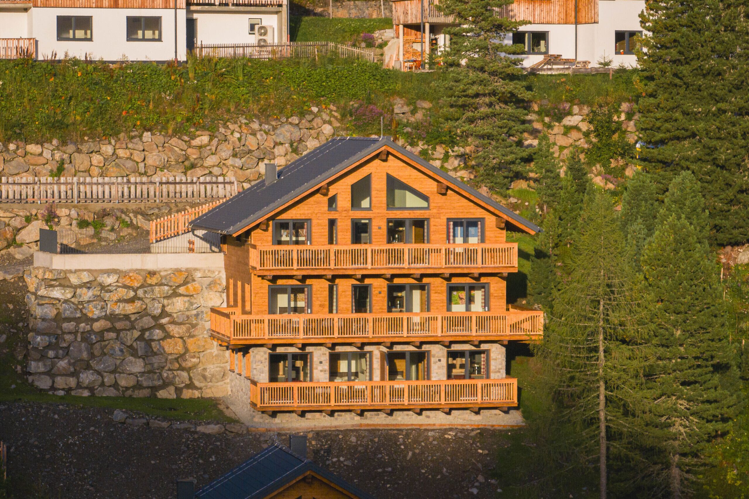 Un edificio in legno a più piani con balconi, sullo sfondo di montagne.