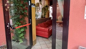 A hotel entrance with a glass door, a red leather sofa inside, and a 'WELCOME' mat outside. - Camelia Rooms Venice Guesthouse near Mestre Train Station - 24 rooms (Venezia)