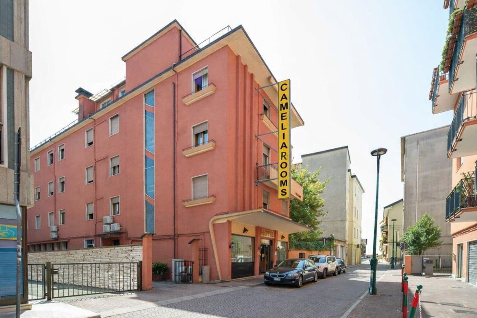 A multi-story hotel with a prominent sign for 'CAMELIA ROOMS' on the facade.