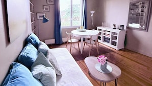 A modern living room with a white sofa, a dining table with chairs, a coffee table with flowers, and a bookshelf. - Le Saint Merry apartment in Fontainebleau in a quiet, central location. (Fontainebleau)