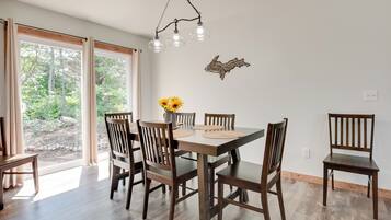Un comedor con una mesa y sillas de madera, una lámpara colgante y un adorno en la pared.
