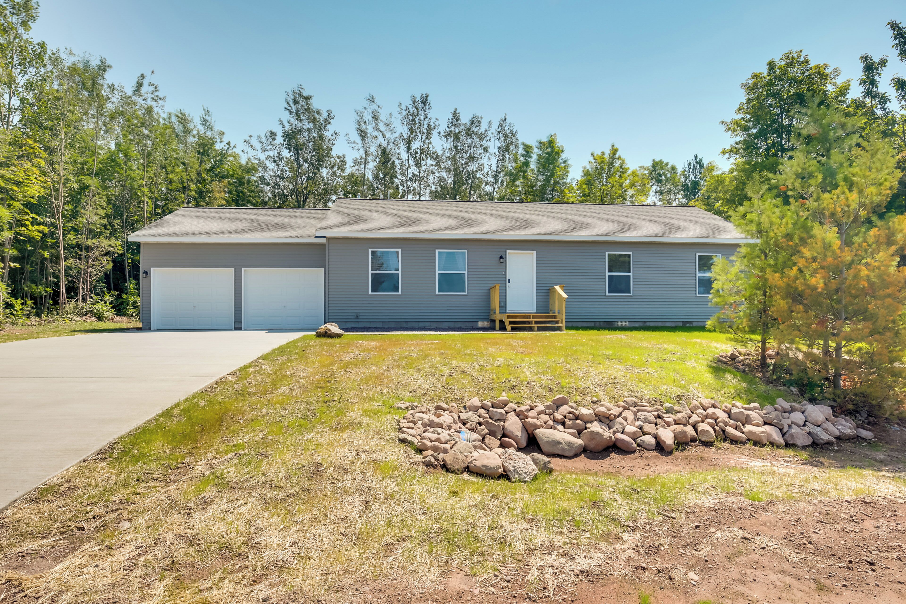 A two-story house with a garage, a front yard with a rock garden, and a small patio area.