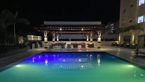 Piscina com área de estar coberta e espreguiçadeiras.
