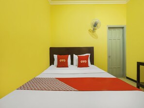 A room with a bed, two pillows with 'OYO' text, a fan, and a door.