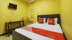 Una habitación de hotel con cama, una silla, televisor y aire acondicionado.