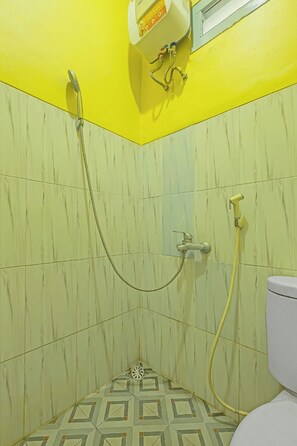 A bathroom with yellow walls, a white toilet, and a shower with a yellow hose.
