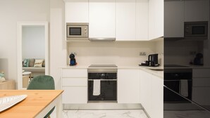 A compact kitchen with white cabinets, a microwave, a coffee machine, and a stove. - Loft Estudio near Las Canteras beach (Las Palmas de Gran Canaria)