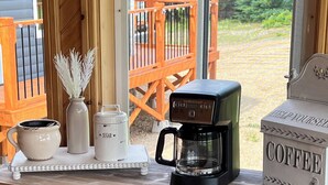 Un escritorio de madera con una cafetera, un azucarero y un jarrón decorativo.