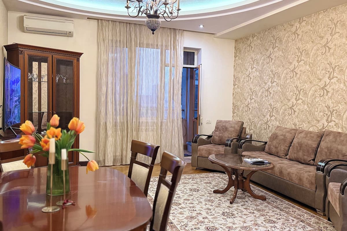 A living room with a sofa, chairs, a coffee table, and a dining table with tulips.