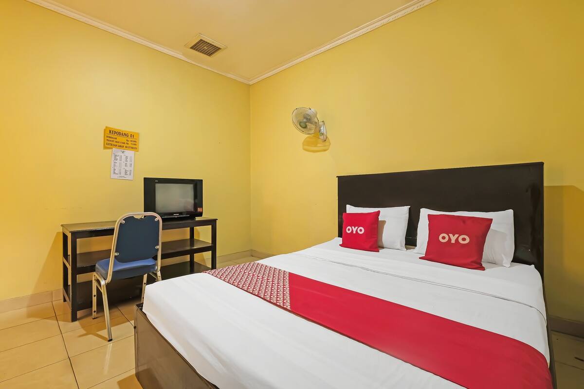 Une chambre d’hôtel avec un lit, un bureau, une chaise, une télévision et un panneau accroché au mur.