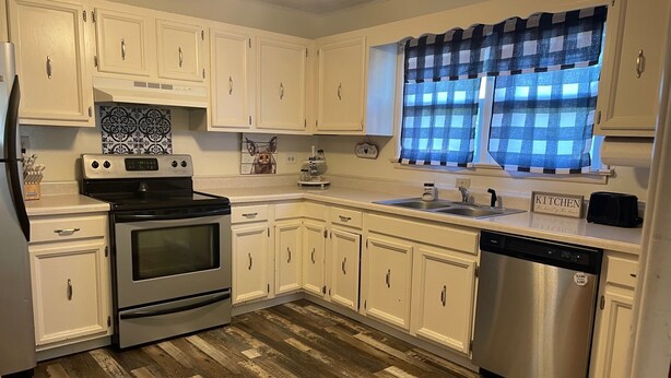A kitchen with white cabinets, a stainless steel dishwasher, and a wooden floor. - Nana's Townhouse centrally located in the Heart of the Ozarks.  (Licking)