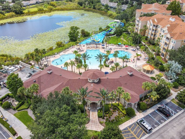 An aerial view of a resort with multiple swimming pools, a water park, and lush landscaping.