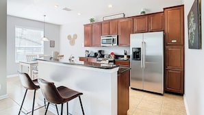 Una cocina moderna con una isla central, electrodomésticos de acero inoxidable y armarios de madera.
