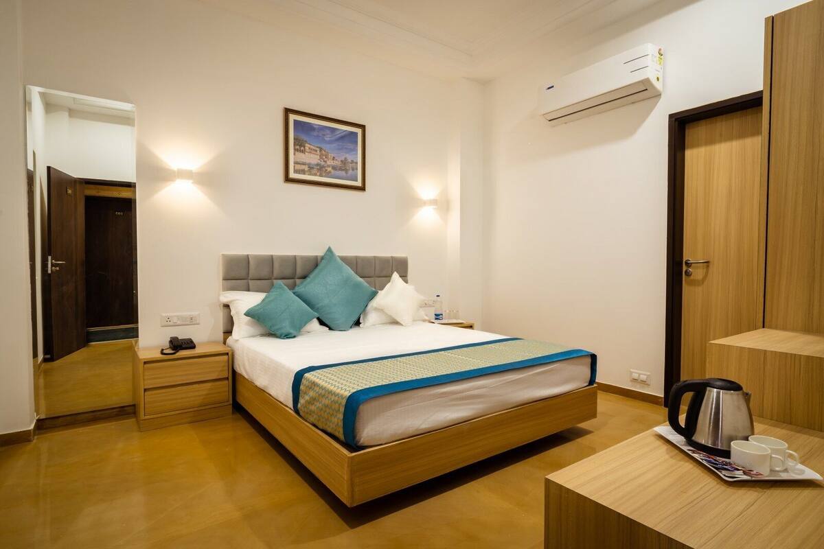 Quarto de hotel com cama, mesa de cabeceira e ar-condicionado fixado na parede.