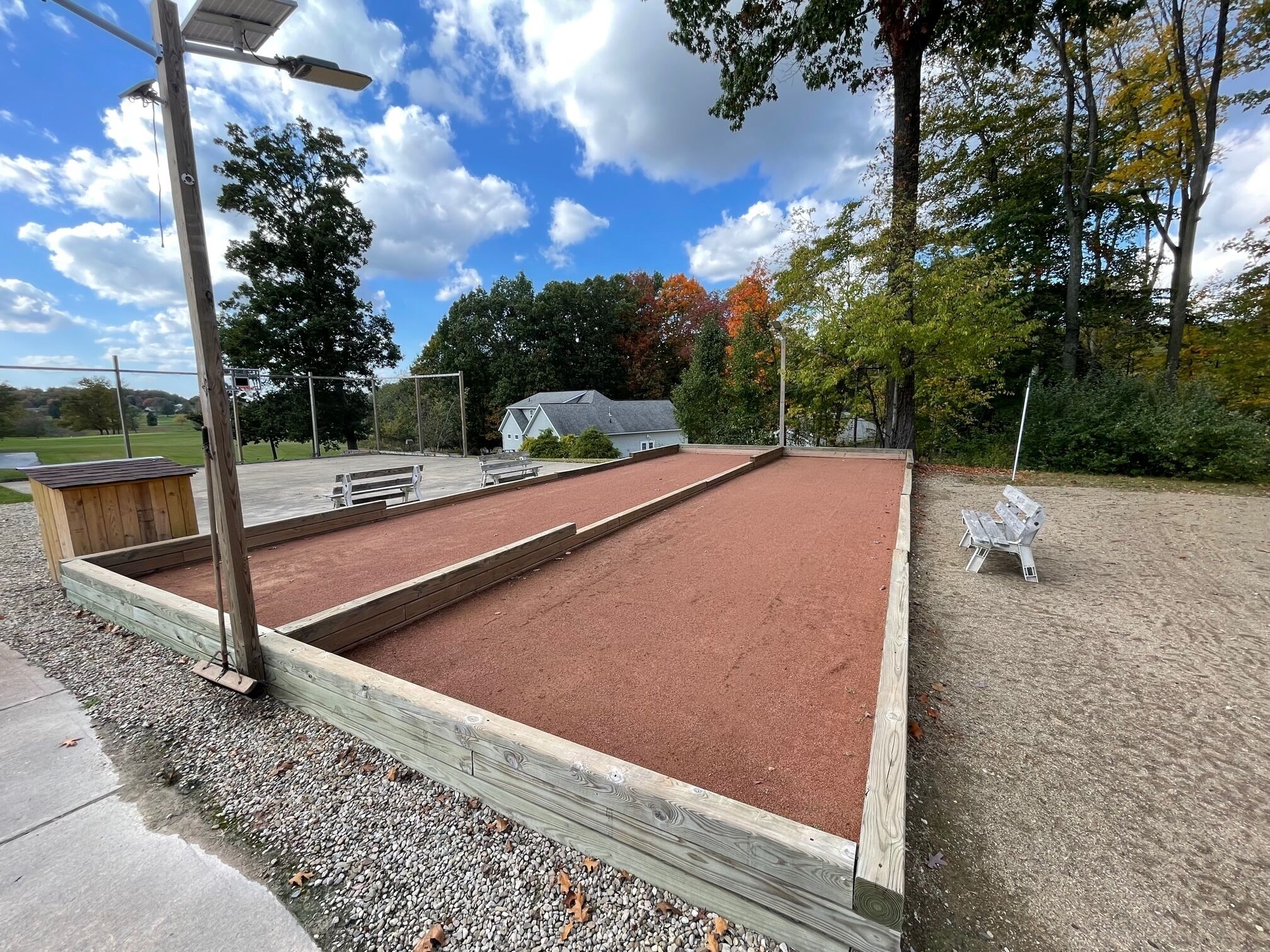 A croquet field with wooden benches and a wooden shed.