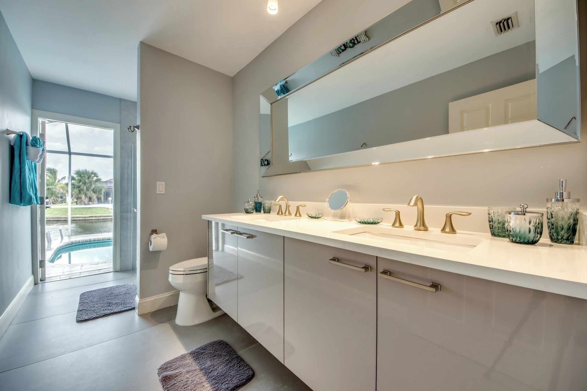 Une salle de bain moderne avec un grand miroir, deux vasques et des toilettes.