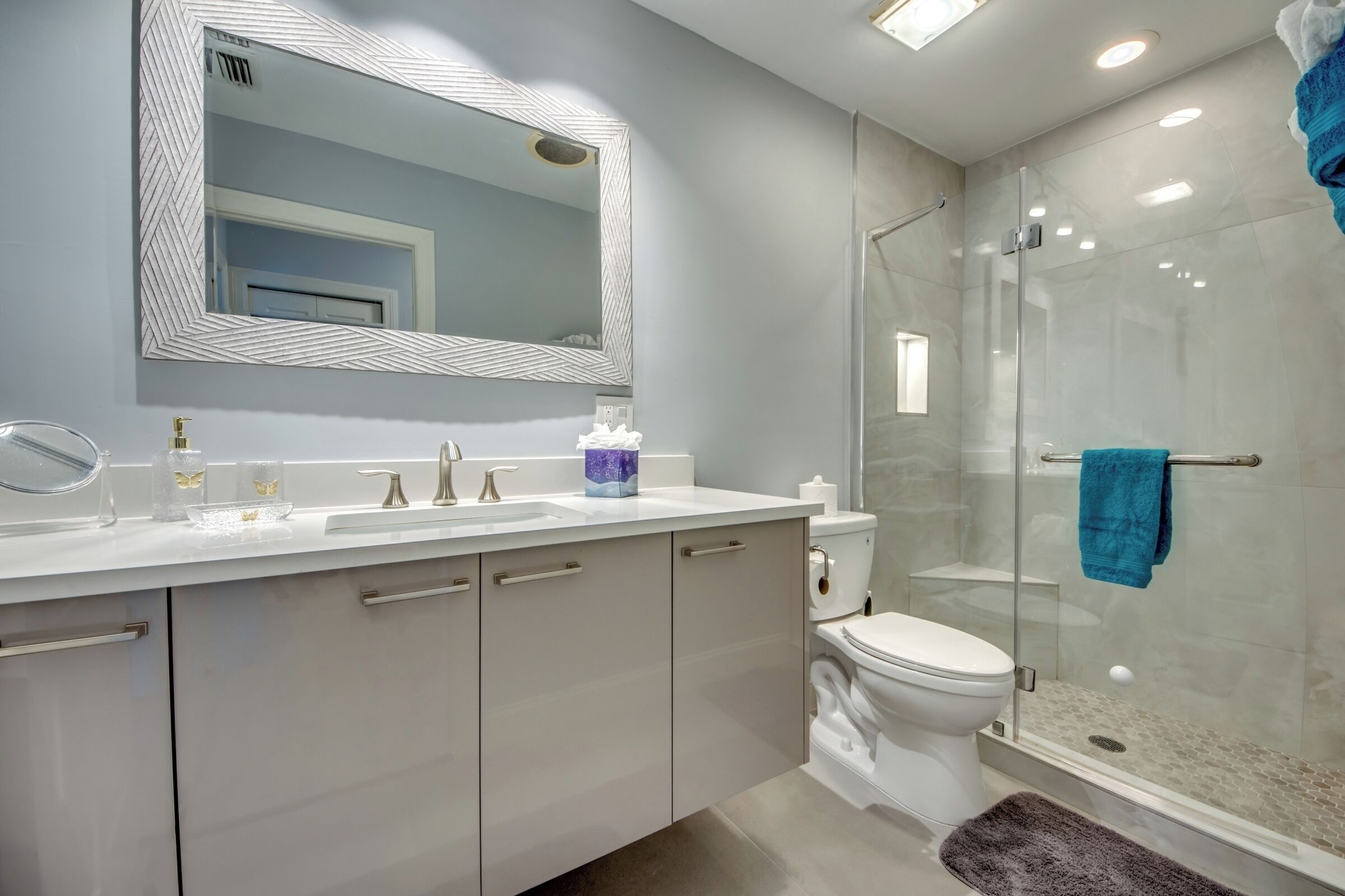 A modern bathroom with a large mirror, a glass shower enclosure, and a white sink.