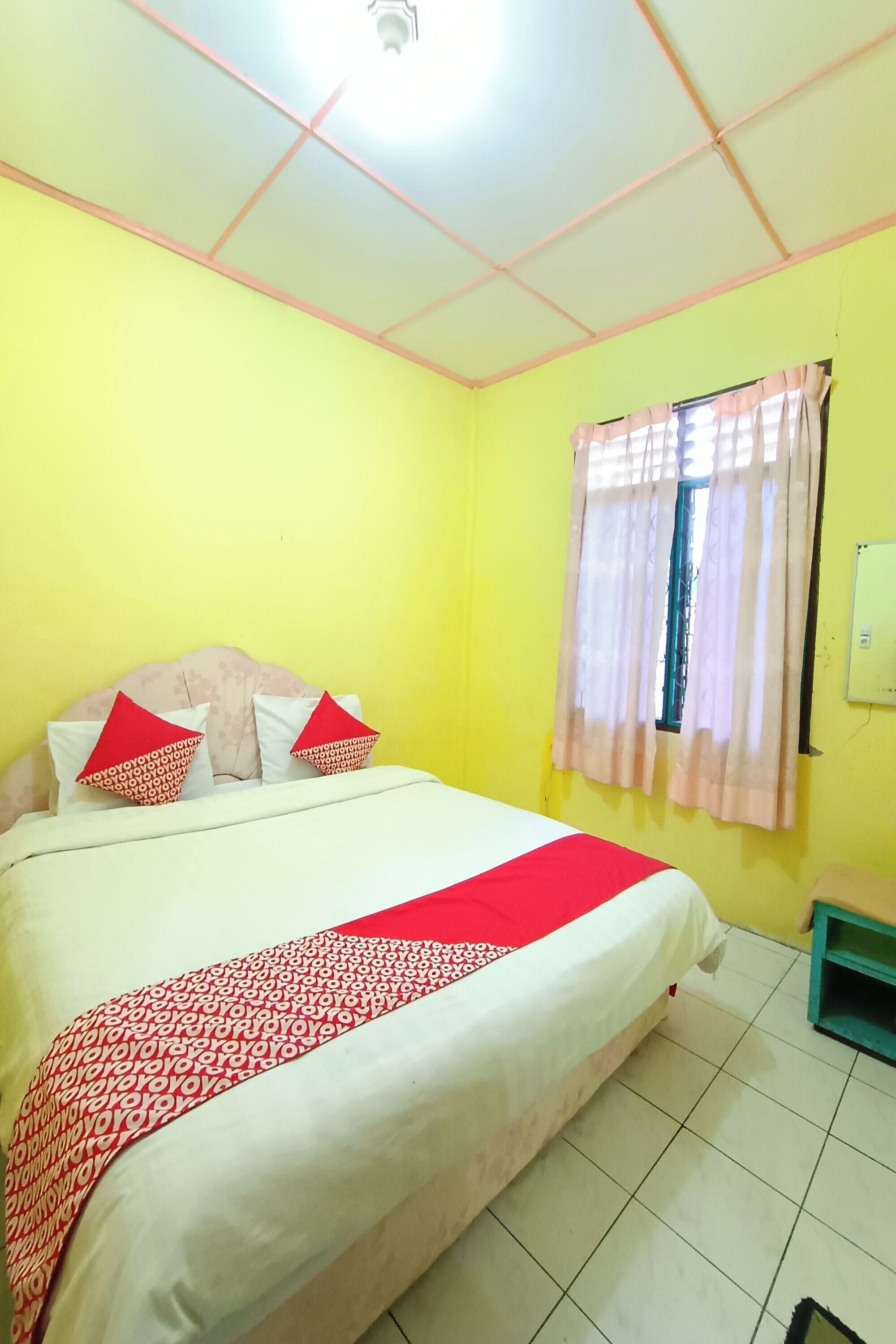 Una habitación con una cama, un ventanal con cortinas y suelo de baldosas.