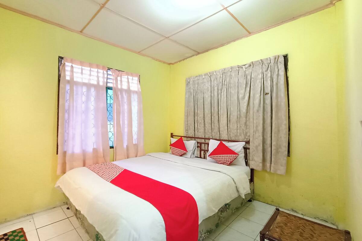 A bedroom with a bed, curtains, and a window.