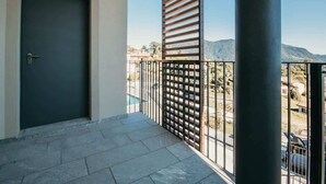 Un balcon avec une porte sombre, une rambarde en métal et une vue sur un paysage montagneux.