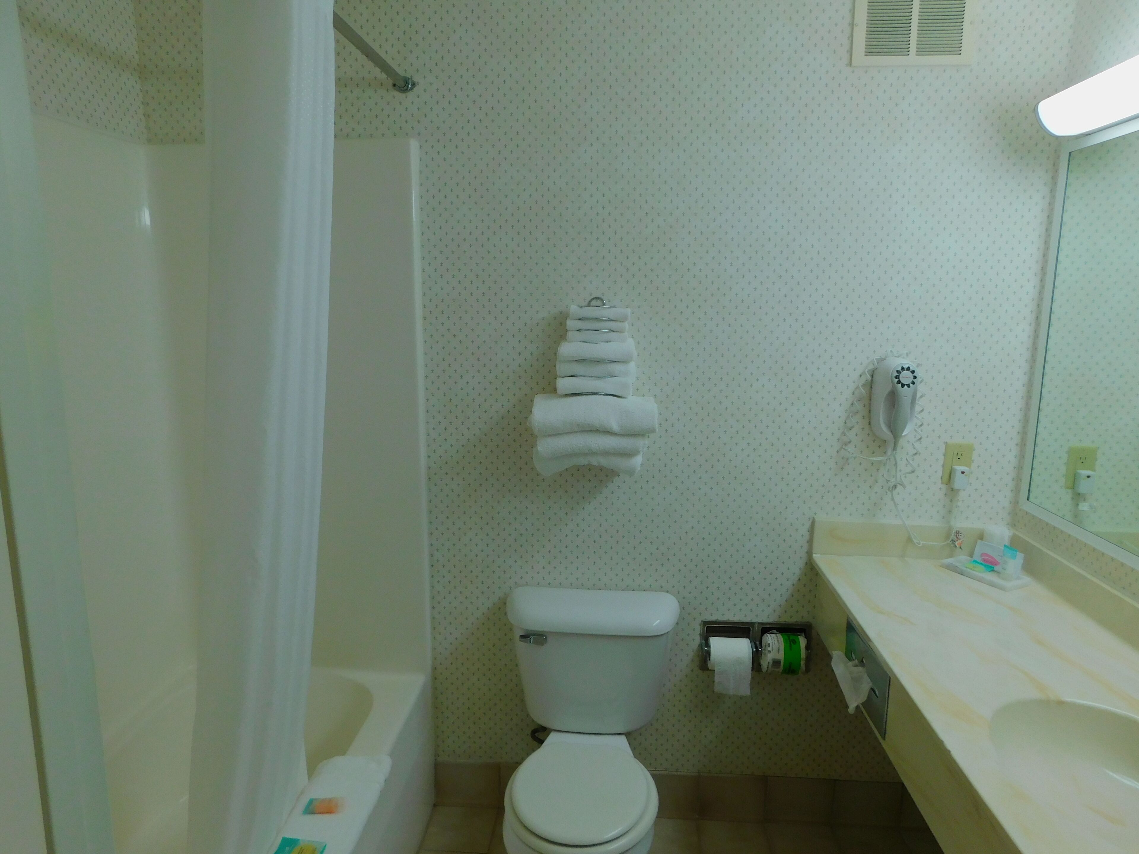 A bathroom with a bathtub, toilet, and a sink with a mirror.