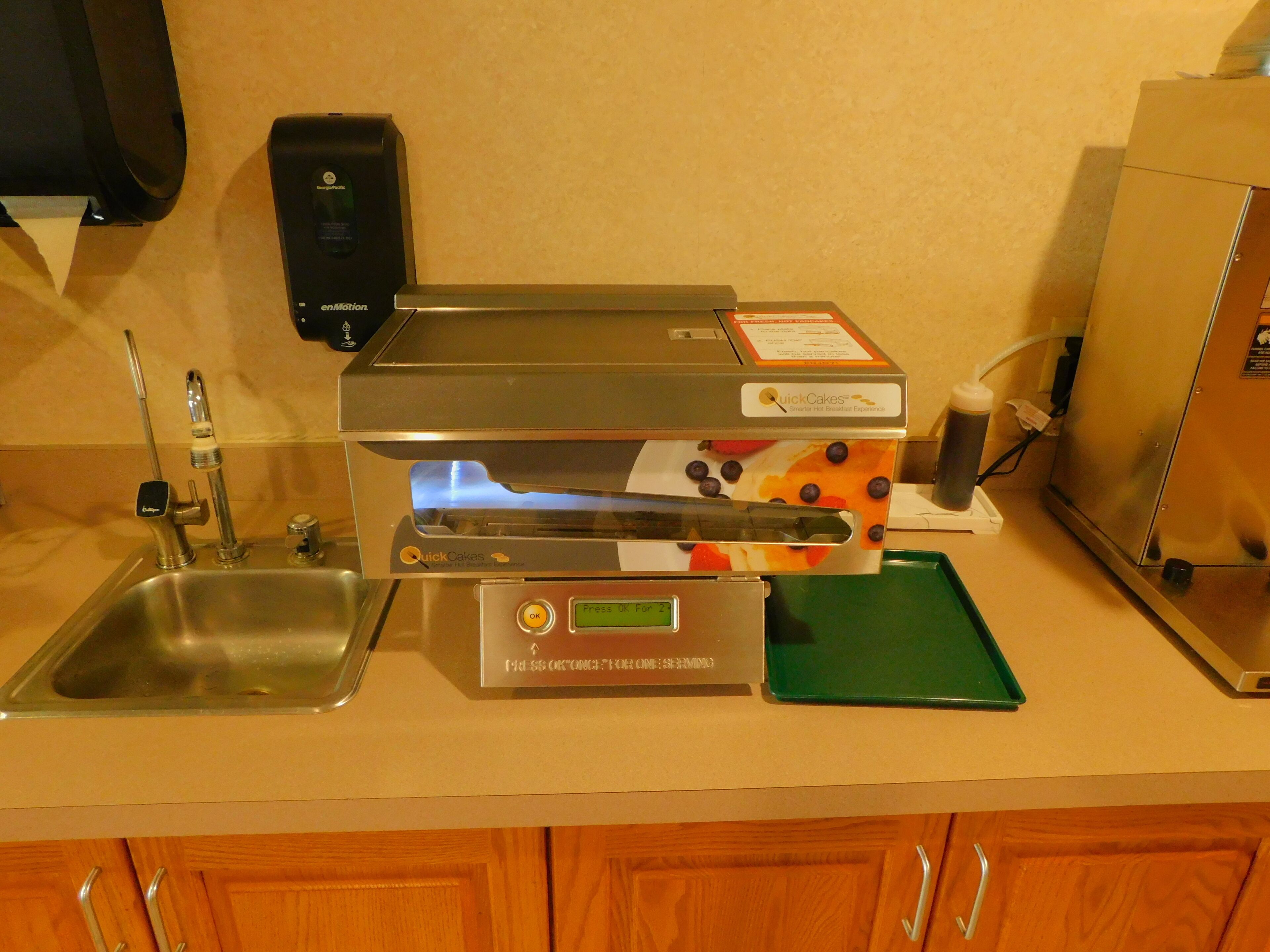 A kitchen with a coffee machine, a sink, and a microwave.