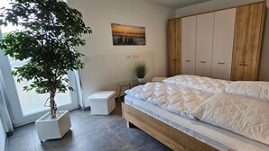 A bedroom with a bed, a wardrobe, a small table with a plant, and a potted tree. - Park - Apartment 10 im Marinapark Scharmützelsee, Sauna, Kamin, 6 Pers., 89 m² (Wendisch Rietz Siedlung)