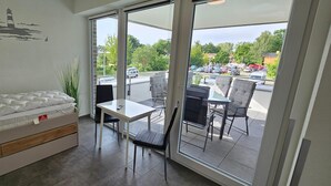 A room with a bed, a table, and chairs, a view of a parking lot and greenery outside. - Park - Apartment 10 im Marinapark Scharmützelsee, Sauna, Kamin, 6 Pers., 89 m² (Wendisch Rietz Siedlung)