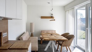 Una cocina moderna con encimera de madera y horno integrado. Hay una zona de comedor con mesa de madera y sillas de mimbre.