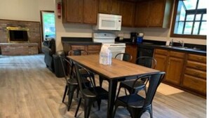 A kitchen with wooden cabinets, a microwave, a stove, and a dining table with chairs.