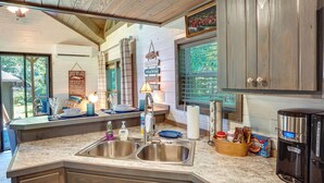 A kitchen with a granite countertop, stainless steel sink, wooden cabinets, and a coffee maker. - Mayfield Tiny Home w/ Porch, Walk to Beaches! (Mayfield)