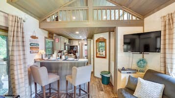 Un intérieur de chalet chaleureux avec un coin bar, des sièges et un téléviseur.