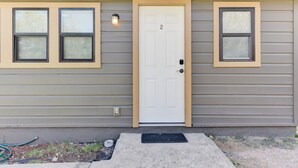 A single-story building with a white door marked with the number 2, flanked by two windows with beige frames. - Downtown - Walk to Wimberley Square! Studio 2 @ Beer Ranch Project Inn (Wimberley)