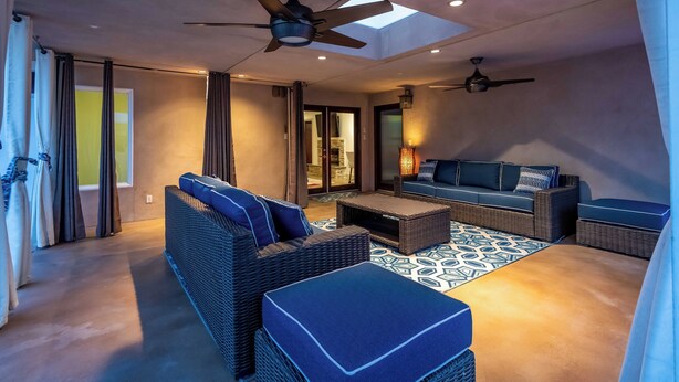 Ein geräumiges Wohnzimmer mit Deckenventilator, einer Couch, einem Couchtisch und einem gemusterten Teppich.
