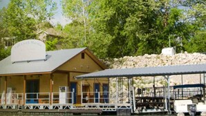 A waterfront building with a covered dock area, a signboard, and a stone wall in the background. - Jack's Cabin-Fall Creek Resort Amenities (Branson)