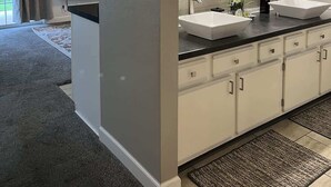 A modern bathroom with two sinks, a large mirror, and a television in the adjacent room. - Jack's Cabin-Fall Creek Resort Amenities (Branson)