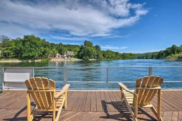 Une terrasse en bois avec deux fauteuils Adirondack donnant sur une rivière.