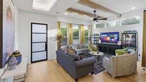 Un salon moderne avec un canapé, un fauteuil, une télévision et des objets de décoration.
