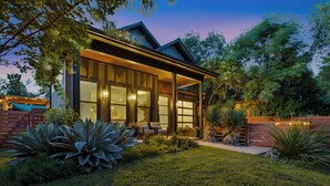 Une maison moderne dotée d’une grande baie vitrée, d’une terrasse en bois et d’un jardin bien entretenu.