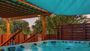Un espace avec un jacuzzi, surmonté d’une pergola en bois, entouré d’une clôture en bois, et agrémenté d’un panneau indiquant la présence d’une piscine.