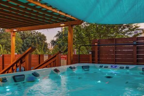 Ein Whirlpoolbereich mit überdachter Holzpergola, Holzlattenzaun und einem Schild, das einen Poolbereich kennzeichnet.